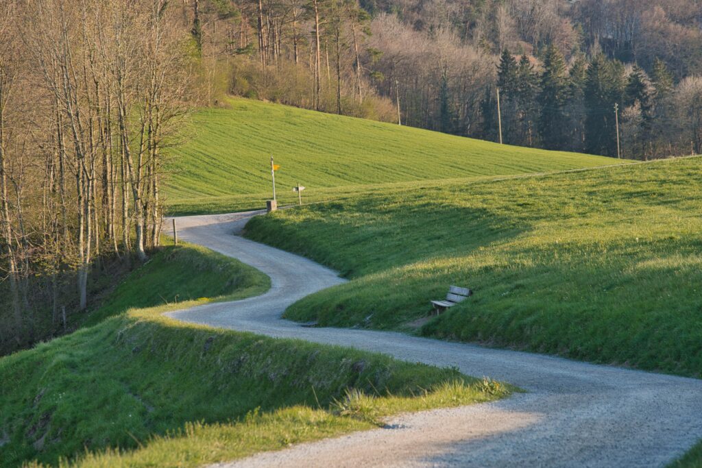 Picturesque winding road through a green countryside during spring, perfect for tranquil, nature-inspired settings.